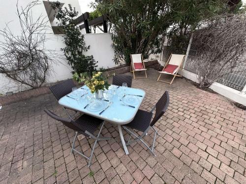 une table bleue et des chaises sur une terrasse en brique dans l'établissement Charmant 2 Pièces avec terrasse et jardin clos, parking inclus - FR-1-731-109, au Grau-du-Roi