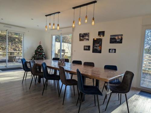 une salle à manger avec une table, des chaises et un arbre de Noël dans l'établissement Grande maison 10 pers. avec bain nordique et jeux près des Vosges - FR-1-589-773, à Frémifontaine