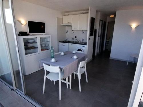 une cuisine avec une table et des chaises dans une pièce dans l'établissement Appartement 3 pièces pour 6 avec piscine, WIFI, et parking à Port Camargue - FR-1-731-108, au Grau-du-Roi