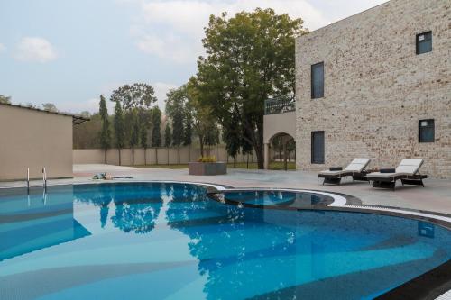 a swimming pool with a patio and a building at SaffronStays Pristine Manor - 8-BR Udaipur villa with private pool, garden, and event space near Fateh Sagar Lake in Udaipur