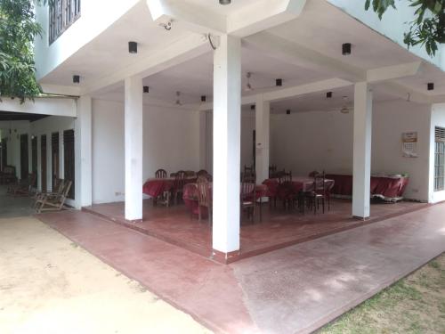 a large white patio with tables and chairs at Jayaru Guest House in Polonnaruwa