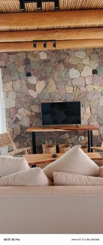 a room with a stone wall with a table and a couch at Entre Cerros in Maimará