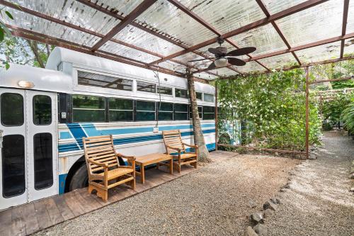 a table and chairs under awning next to a bus at Balu Retreat Center in Playa Junquillal