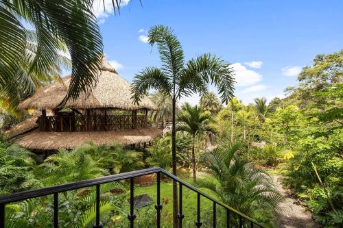 a resort building with a thatched roof and palm trees at Balu Retreat Center in Playa Junquillal