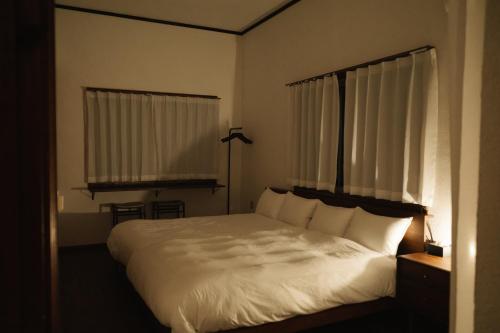 a bedroom with a bed with white sheets and a window at ASAHi in Ikei