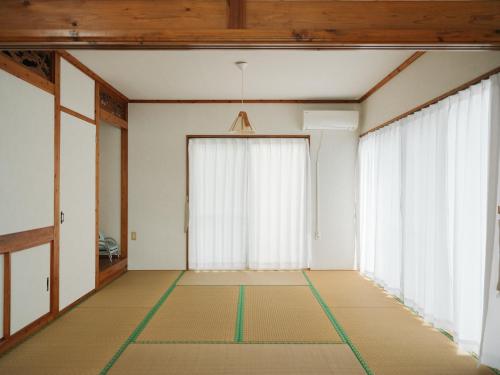 an empty room with white walls and large windows at ASAHi in Ikei