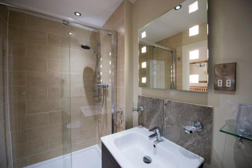 uma casa de banho com um lavatório, um chuveiro e um espelho. em Elmdene em Torquay