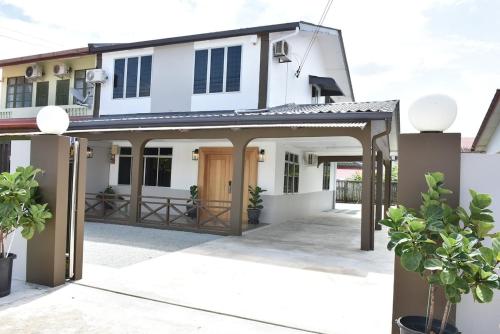 a white house with a gate and a porch at Rain Tree Homestay in Bintulu