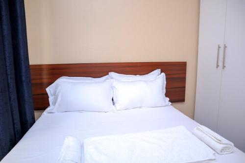 a white bed with white pillows and a wooden headboard at Elegant 3 Bedroom Apartment - 1255 Palm Ridge in Vipingo
