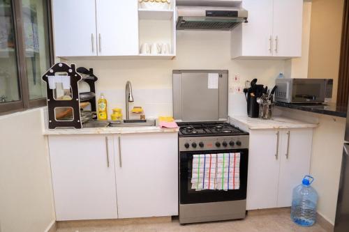 a kitchen with white cabinets and a stove at Elegant 3 Bedroom Apartment - 1255 Palm Ridge in Vipingo