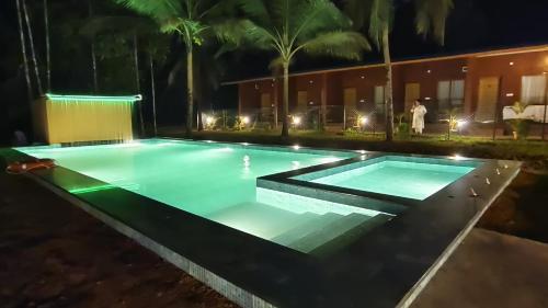 a swimming pool at night with people standing around it at West Coast Gokarna in Gokarna