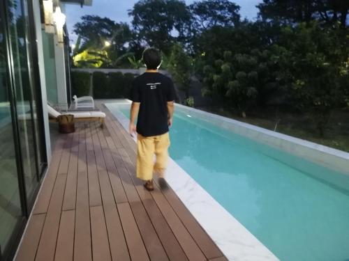 a man walking by a swimming pool at AP HOUSE in Bangkok