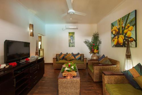 a living room with couches and a flat screen tv at Le Relax Beach Resort in Grand'Anse Praslin