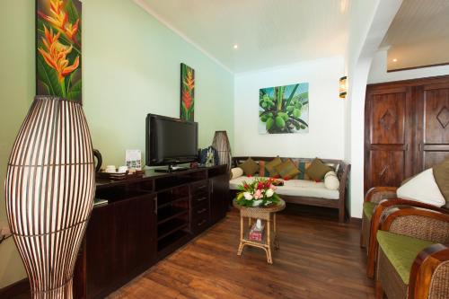 a living room with a television and a couch at Le Relax Beach Resort in Grand'Anse Praslin