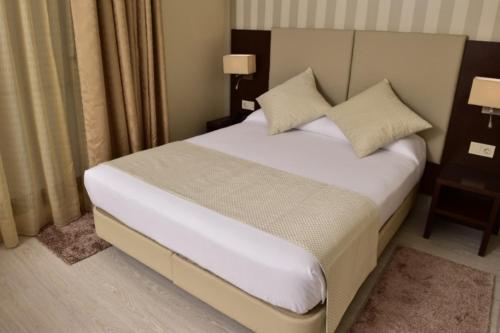 a bedroom with a bed with white sheets and pillows at AZ Hôtels Zeralda in Zeralda