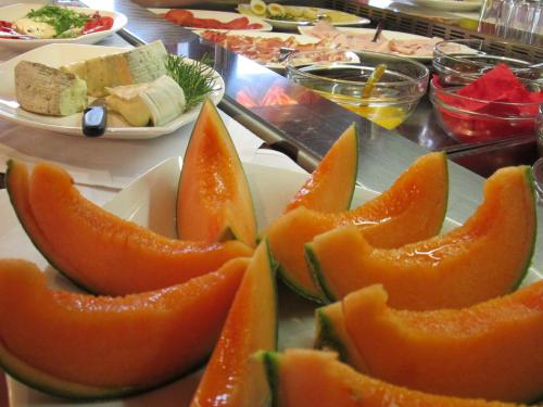 a table topped with plates of food with orange fruits at Hotel Schönbrunn in Merano