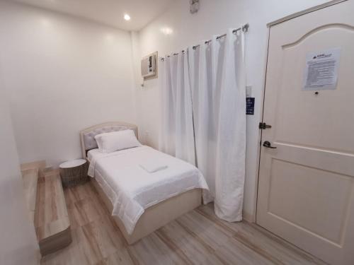 a small bedroom with a bed and a door at Acrige Apartelle Studio Rooms at heart of Bogo City in Bogo