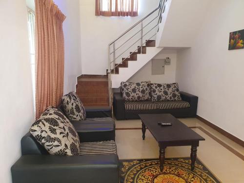 a living room with a couch and a table and stairs at Peters Park in Yelagiri