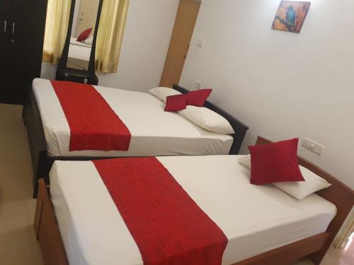 two beds in a room with red and white at Peters Park in Yelagiri