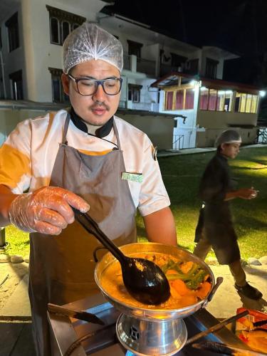 a man is stirring a pot with a spoon at Silver Cloud Hotel in Paro