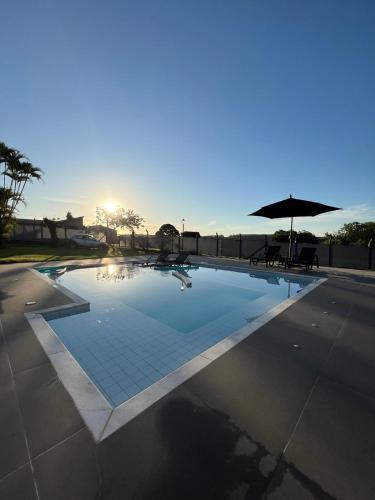 a swimming pool with an umbrella and a table and chairs at Country house with pool wifi and perfect view in Itapetininga