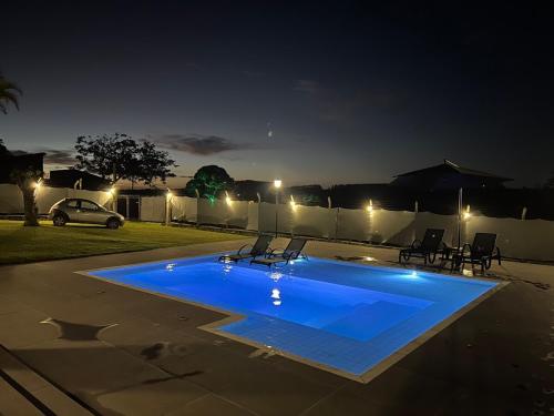 a blue swimming pool in a yard at night at Country house with pool wifi and perfect view in Itapetininga