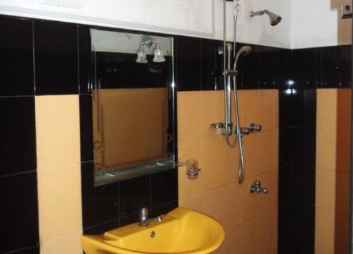 a bathroom with a yellow sink and a shower at Travellers Halt in Ratnapura