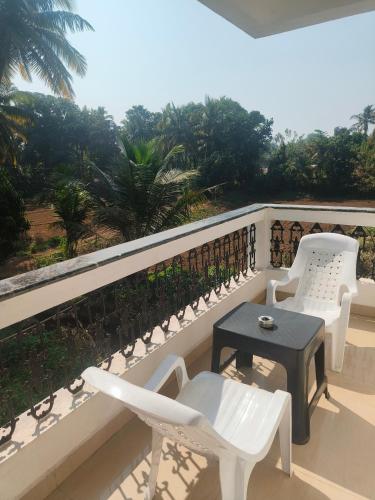 a balcony with white chairs and a table at Villa NAMAKA in Morjim