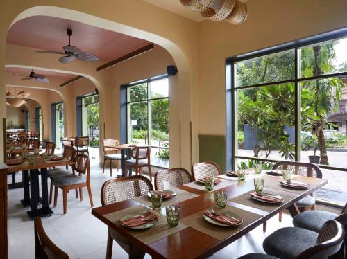 a restaurant with tables and chairs and large windows at Radha House Siolim A Boutique Hotel in Oxel