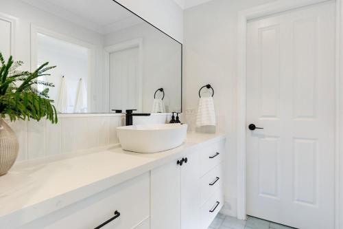 ein weißes Badezimmer mit Waschbecken und Spiegel in der Unterkunft Newly Renovated Cottage sleeps 6 in Lake Albert