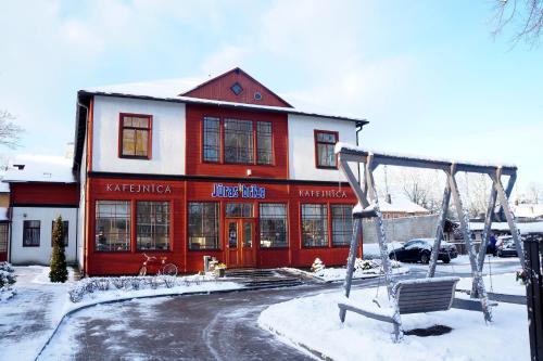 a red and white building with a swing in the snow at Jūras Brīze in Ventspils