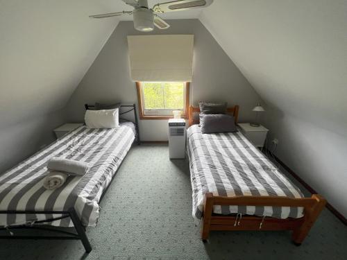 une chambre mansardée avec deux lits et une fenêtre dans l'établissement Shinglers Cottage, à Mayers Flat