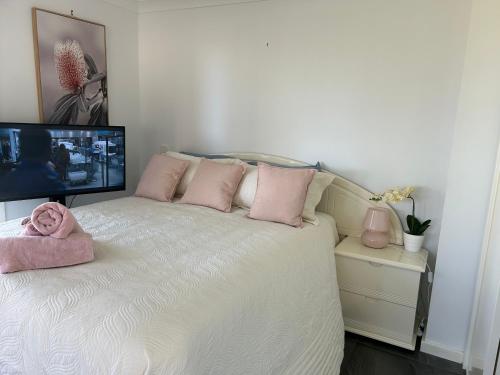 una camera con letto, cuscini rosa e TV di Waters Edge Luxury Lakeside Studio a Rocky Point