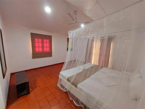 a bedroom with a bed with a mosquito net at Helios Beach Resort in Tangalle