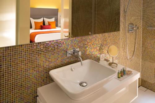 ein Badezimmer mit einem Waschbecken und ein Schlafzimmer mit einem Bett in der Unterkunft Hotel D - Design Hotel in Basel