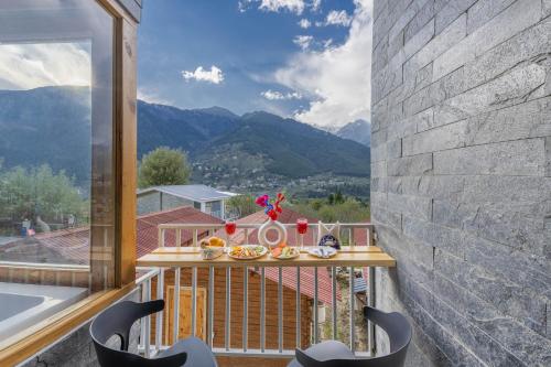 a balcony with a table and chairs and a view of mountains at Echor Himalayan Heights Luxe Manali in Manāli