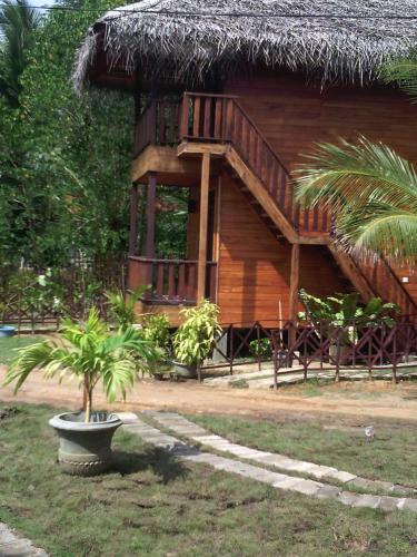 a wooden house with a tree in front of it at Eco Cabanas Marakolliya in Tangalle