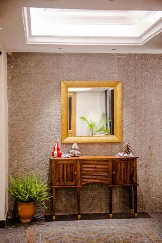 a mirror on a wall with a wooden dresser at Eden Wellness and Hospitality in Dehradun