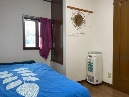 a bedroom with a blue bed and a air conditioner at 福島小月 in Niiza