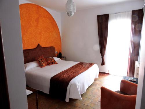 a bedroom with a large bed and a chair at Hotel La Fonda del Califa in Arcos de la Frontera