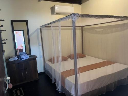 a bedroom with a canopy bed and a mirror at Cozylane in Arugam Bay