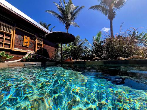 a swimming pool in front of a house with palm trees at OHANA Jungle Lodges in Les Avirons