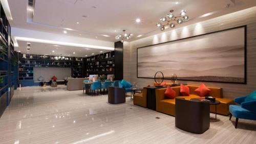 a library with couches and chairs and a large screen at GRACE Select Hotel (Kunshan Huaqiao International Convention Center) in Suzhou