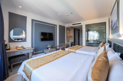 a large bedroom with two beds and a desk at Ruby Hotel in Nha Trang