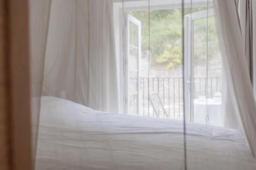 a white bed in front of a window at Rock Mill Retreat in Stoney Middleton
