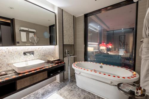 une salle de bain avec une baignoire, un lavabo et un miroir dans l'établissement Braira Al Dammam, à Dammam