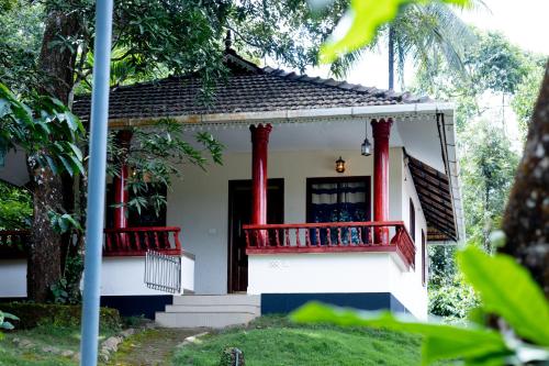 a small house with red columns and a balcony at Green Garden Wayanad Villas in Vayittiri