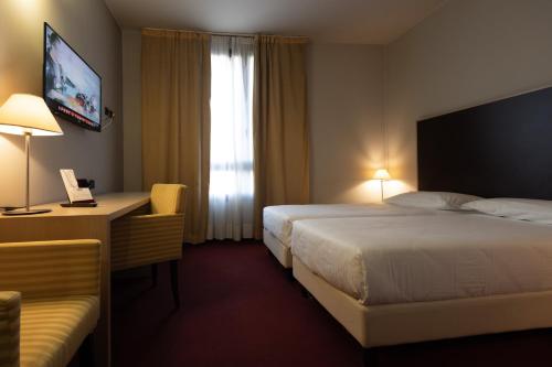 a hotel room with a bed and a desk and a window at Art Hotel Olympic in Turin