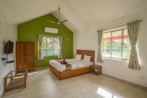 a bedroom with a bed and a green wall at Gardan 2BHK Villa Alibaug in Alibaug