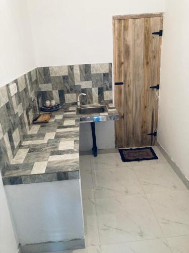 a bathroom with a sink and a wooden door at Vintage Rest Anuradhapura in Anuradhapura
